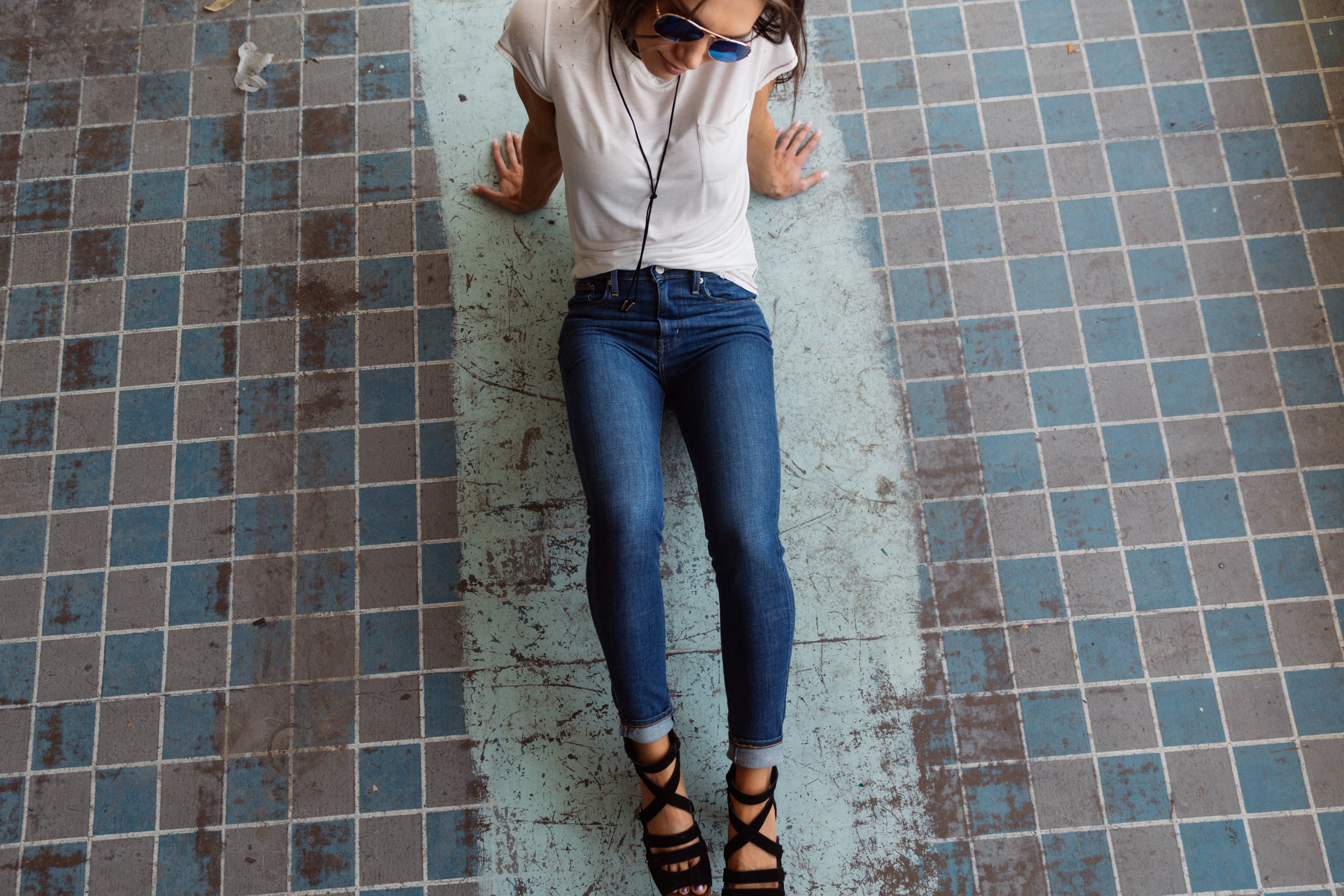 Girl sitting on tile floor in Mile High Waisted Levi's skinny jeans.