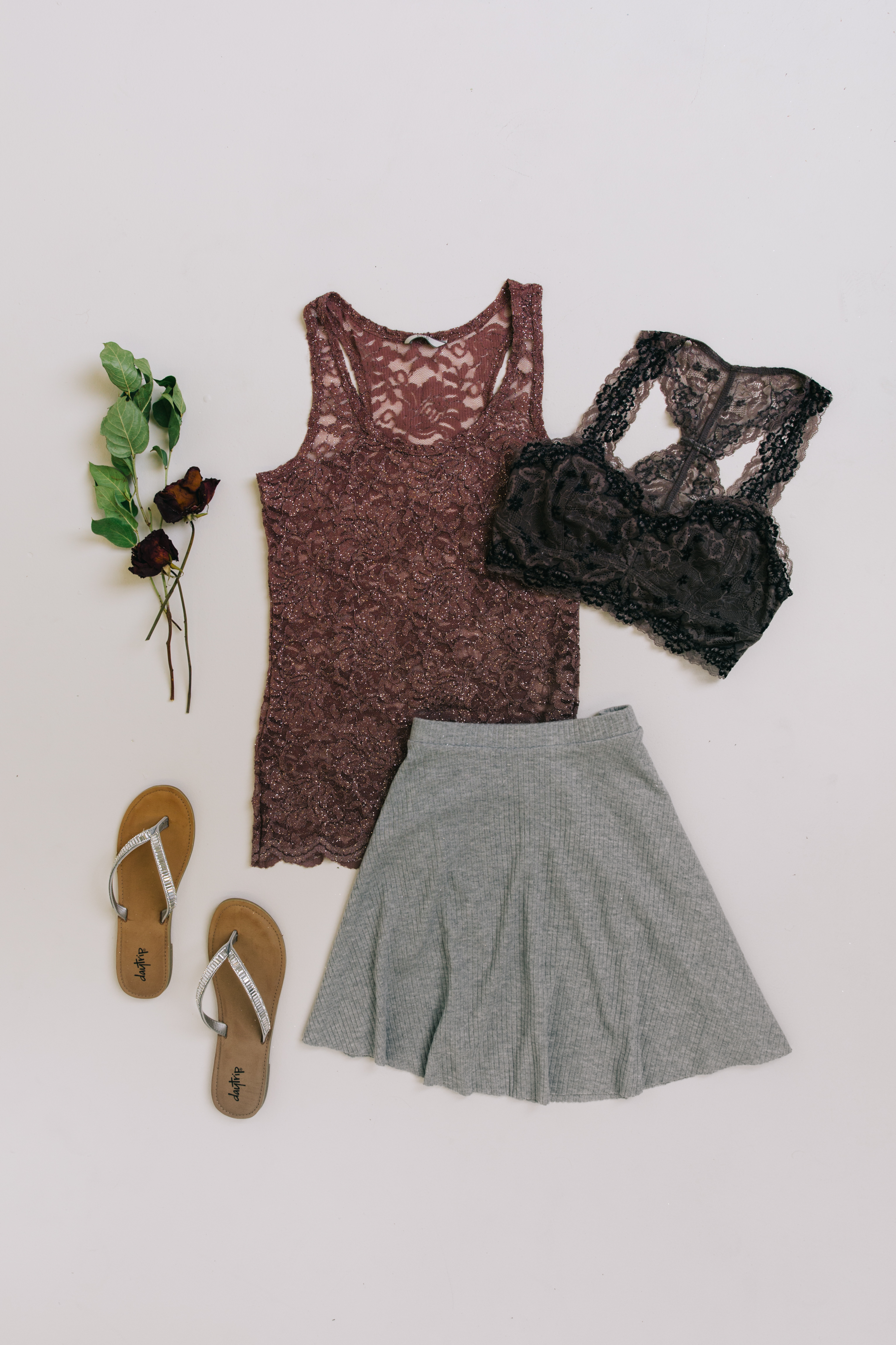 Laydown of a grey skater skirt, mauve lace tank top, and black bralette.