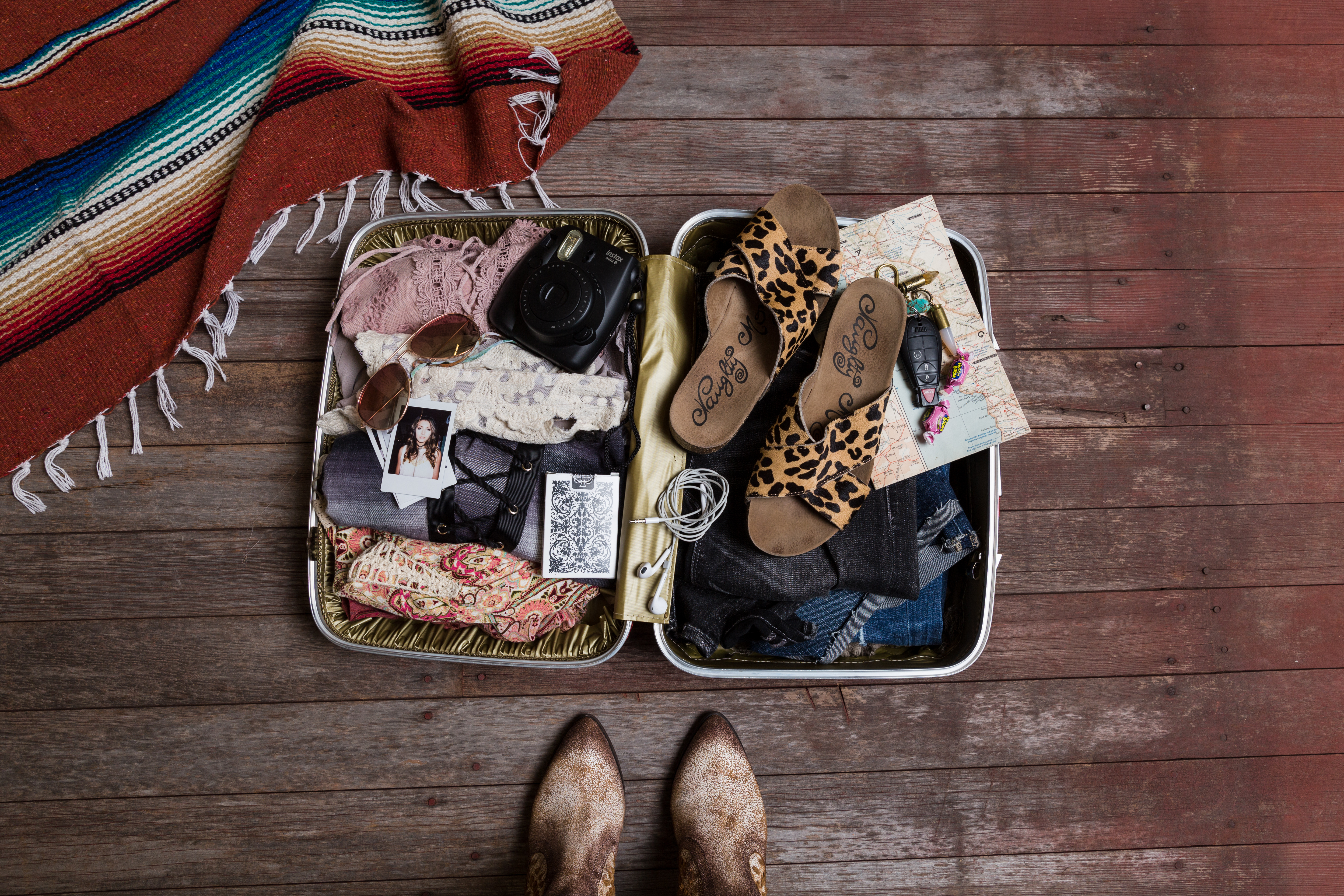 laydown of woman standing over packed suitcase